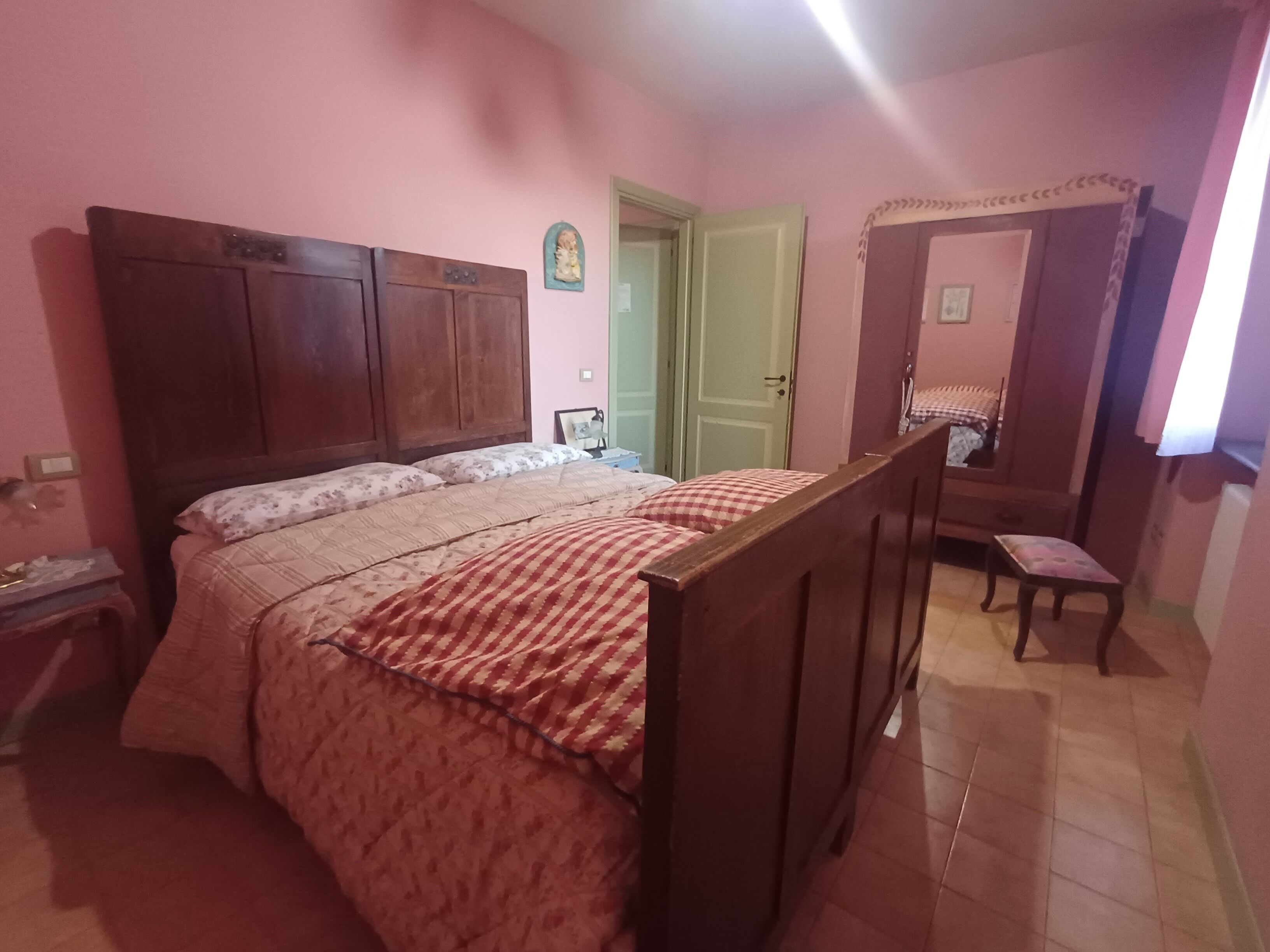 A bedroom with a wooden bed, a nightstand, a chair, and a wardrobe.