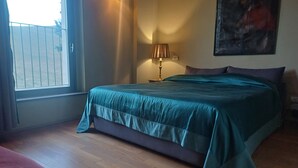 A bedroom with a bed, a nightstand, a lamp, and a painting on the wall.