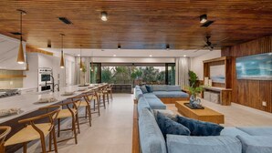 A modern kitchen with white cabinets and a dining area with wooden chairs and a long table.