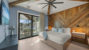 A modern bedroom with a large bed, a wooden accent wall, and a view of the outside balcony.