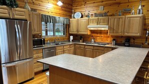 Une cuisine moderne avec des meubles en bois, des appareils électroménagers en acier inoxydable et un grand îlot central.