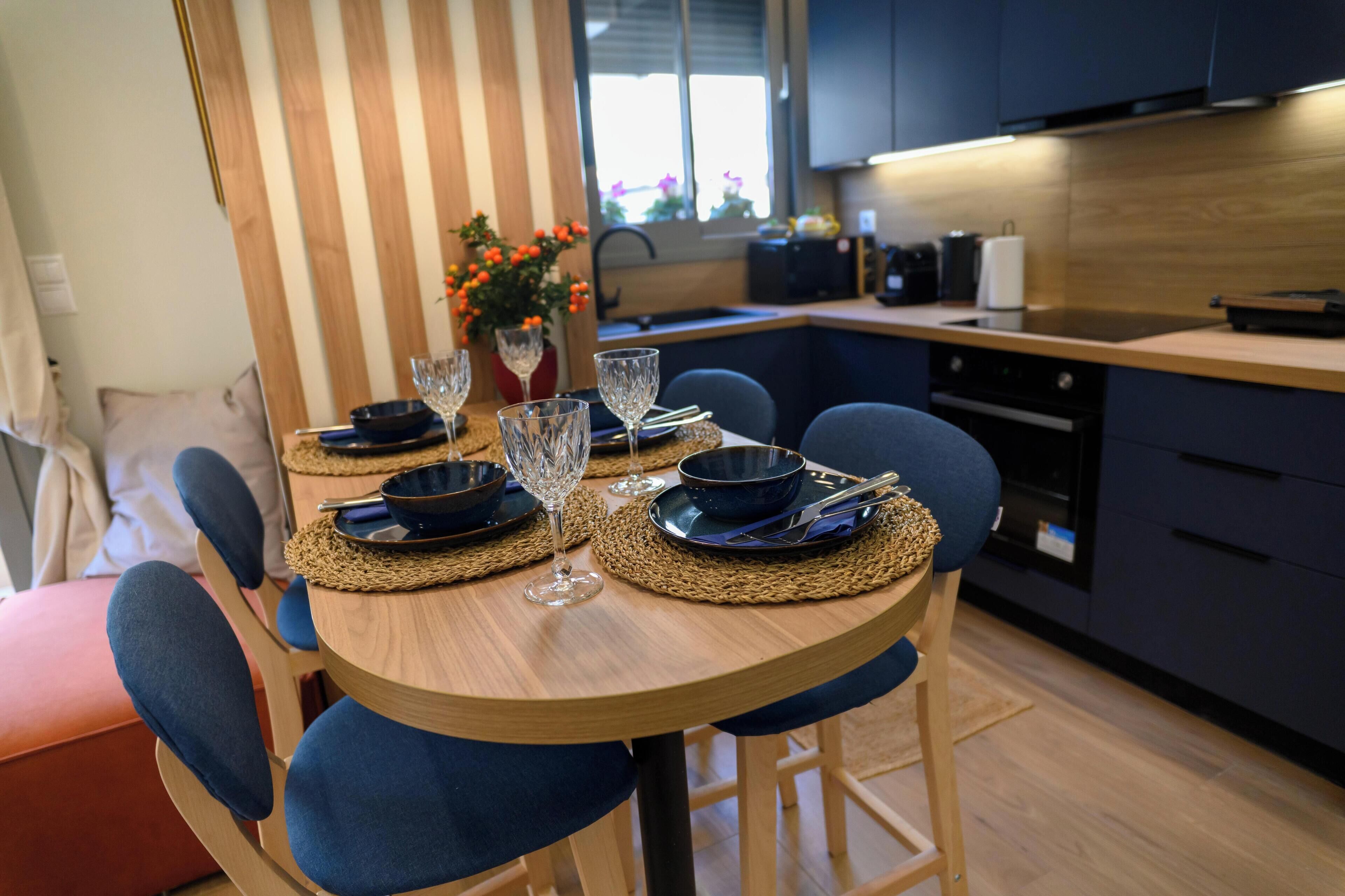 A dining area with a wooden table set for four, surrounded by blue chairs.