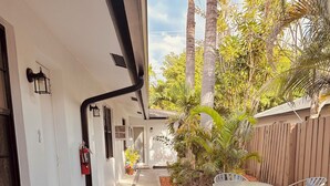 A pathway leading to a patio area with a table and chairs, surrounded by plants and a wooden fence. - Charming Getaway with WiFi, AC in delightful Fort Lauderdale (Fort Lauderdale)
