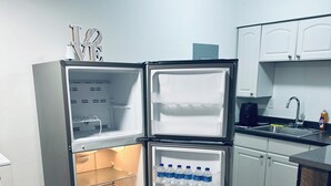 A compact kitchen with a built-in refrigerator, a sink, and a coffee maker. - Charming Getaway with WiFi, AC in delightful Fort Lauderdale (Fort Lauderdale)