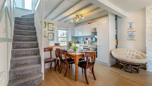 A dining area with a wooden table, chairs, and a cushioned chair. A staircase is visible on the left. - 3 Bed in Brixham (oc-p30777) (Brixham)