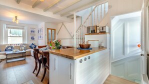 A kitchen with a wooden island, white cabinetry, and a dining area with a sofa and chairs. - 3 Bed in Brixham (oc-p30777) (Brixham)