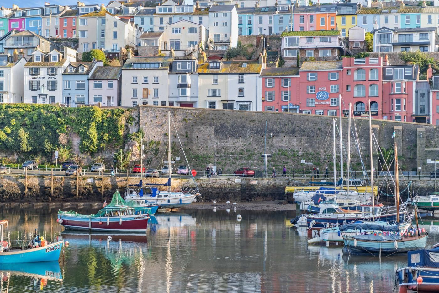 A harbor with colorful buildings, boats, and a rocky cliff.