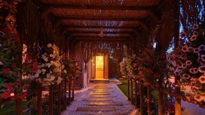 Un sendero bordeado de postes de madera y decoraciones florales que lleva a la entrada de un edificio.