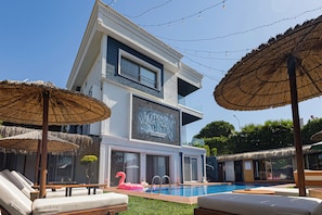 A modern building with a swimming pool, lounge chairs, and thatched umbrellas. - Mistral Alaçatı Hotel (Çesme)