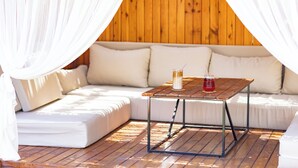 Un espacio al aire libre acogedor con una mesa de madera, cojines blancos y un toldo.