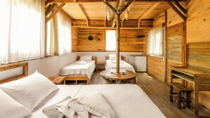 Una cabaña de madera con dos camas individuales, una mesita y un banco.