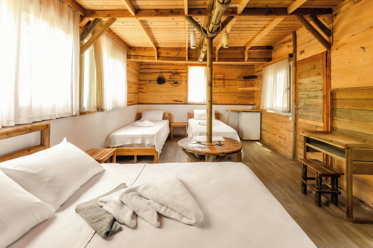 A wooden cabin with two single beds, a small table, and a bench.