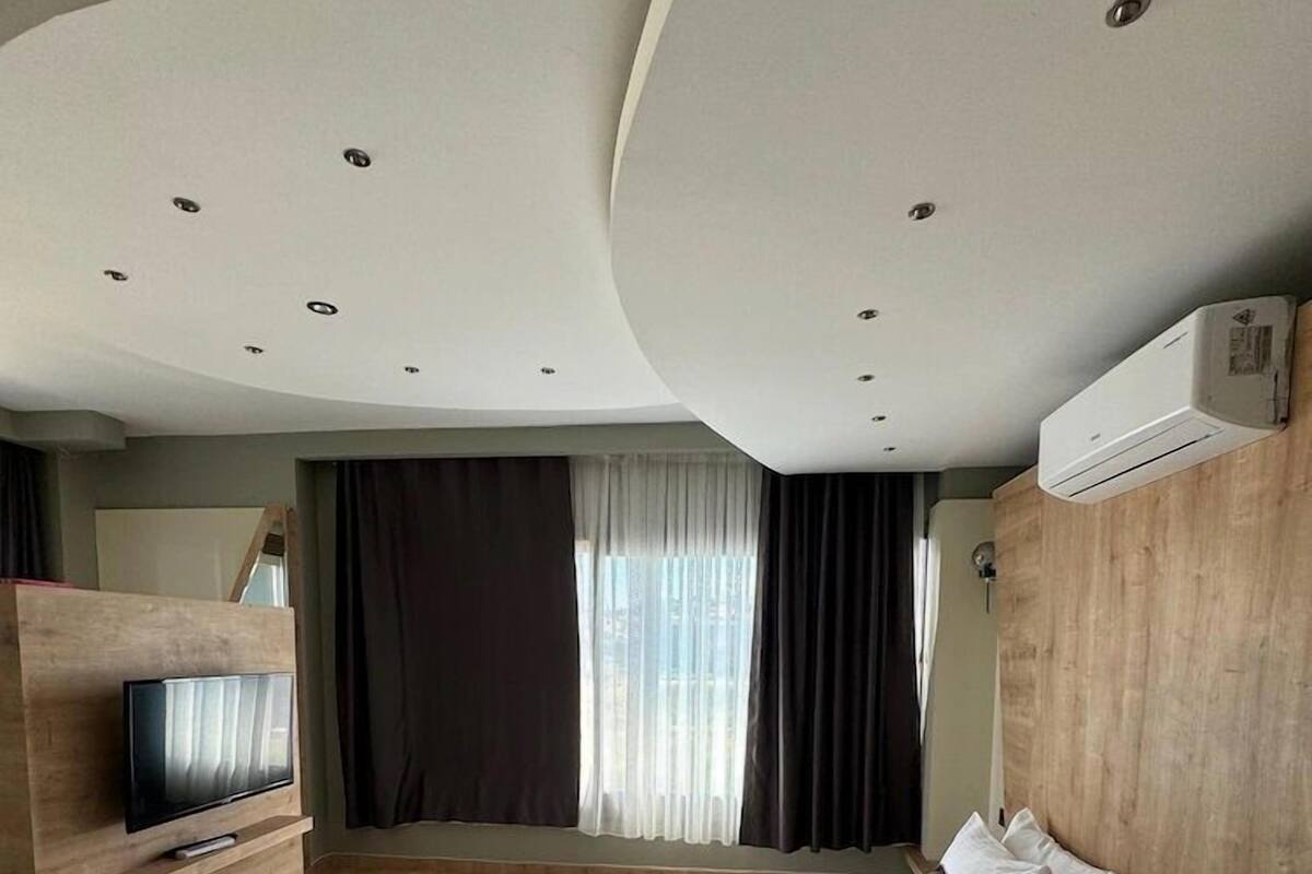 A modern hotel room with a large bed, a TV, and a wooden headboard.