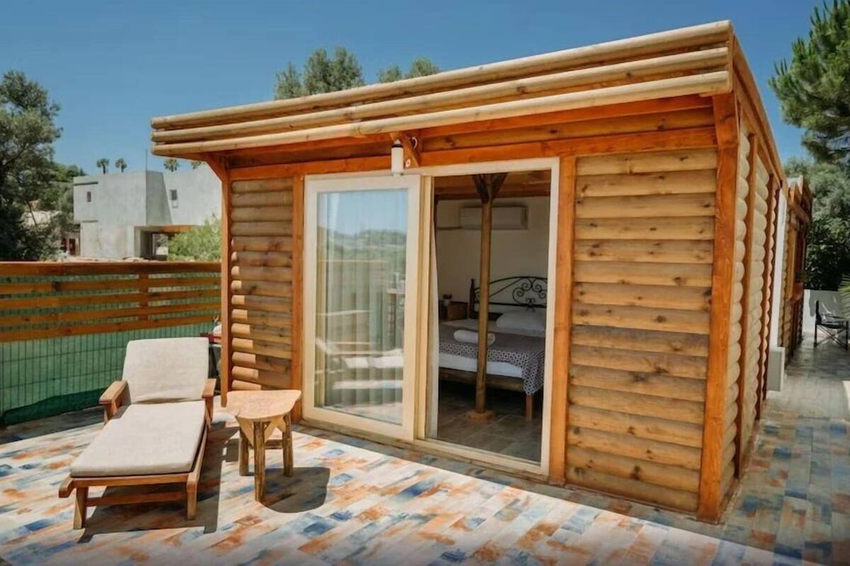 A small wooden cabin with a balcony, a bed, and a seating area.