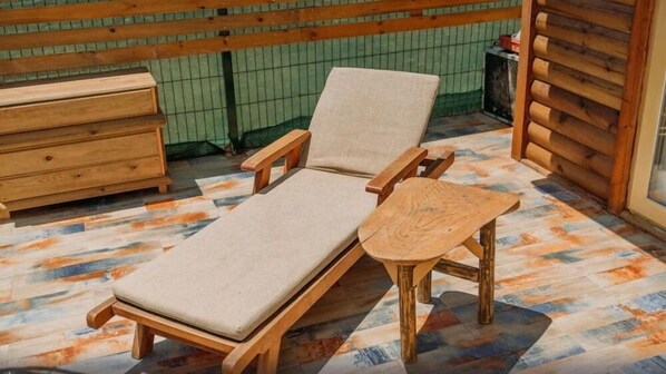 A wooden lounge chair with a cushion and a small wooden table on a patterned floor. - Mistral Alaçatı Hotel (Çesme)