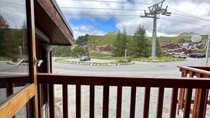 A wooden balcony with a metal railing overlooking a parking area and a mountainous landscape. - 200m from resort center, view forest, terrace, balcony, fireplace or stove, tv, 42m², La Plagne (La Plagne)