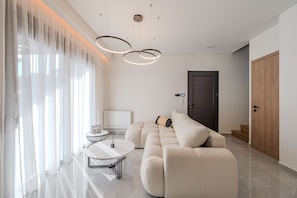 A modern living room with a sectional sofa, a round coffee table, and a large window with sheer curtains.