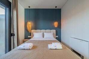 Una habitación de hotel moderna con una cama grande, dos lámparas de noche, una mesita de noche y un equipo de aire acondicionado integrado.