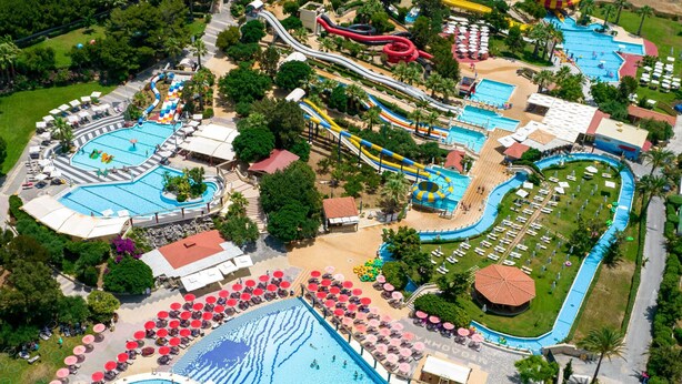 Vue aérienne d’un complexe hôtelier doté de plusieurs piscines, de toboggans aquatiques et de chaises longues.