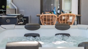 Un bain à remous au design moderne, un coin repas avec des chaises en osier et une vue sur l’extérieur.