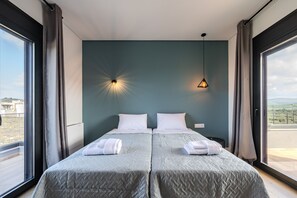 Et hotelværelse med to senge, et stort vindue og udsigt over landskabet.