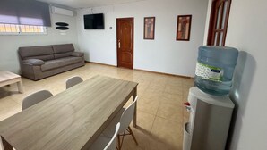 A living room with a sofa, a dining table, chairs, a water dispenser, and a television. - La Colina Rural House El Duque Accommodations (Córdoba)