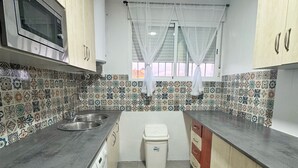 A kitchen with a microwave, washing machine, and tiled backsplash. - La Colina Rural House El Duque Accommodations (Córdoba)