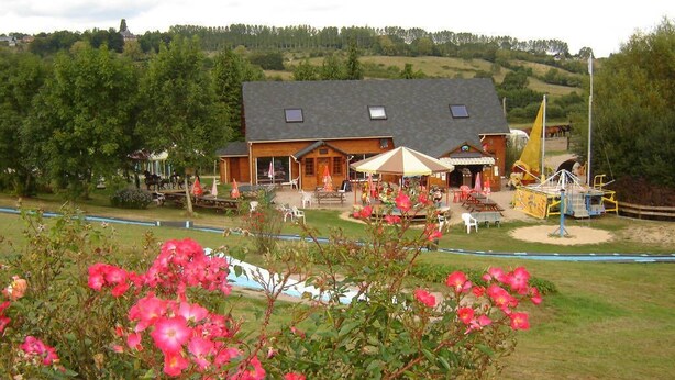A lodge with a large building, outdoor seating, and a swimming pool. - Rental of comfortable trailers for 4 people at DEVALPARC leisure park (Livarot-Pays-d'Auge)