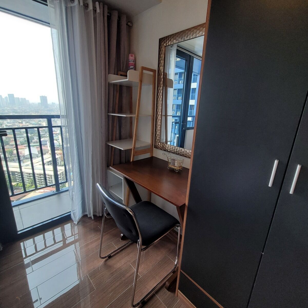 A bedroom with a wooden desk, a chair, a mirror, and a wardrobe.