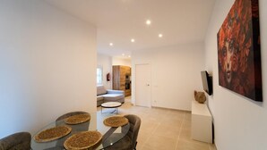 Ein modernes Wohnzimmer mit einem Glastisch, einem grauen Sofa und einem Gemälde an der Wand.