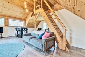 Ein Loft-Zimmer mit einer Holztreppe, einer Couch und einem Essbereich.