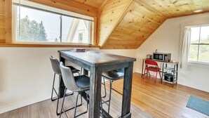 Un loft con techo de madera, una mesa de comedor con sillas, una kitchenette y ventanas amplias.
