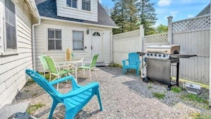 Een huis met een overdekte patio, buitenmeubels en een barbecue.