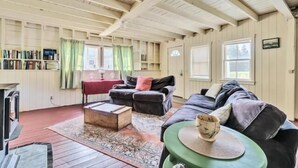 Een gezellige kamer met een open haard, een bank, een bijzettafeltje en een boekenkast.