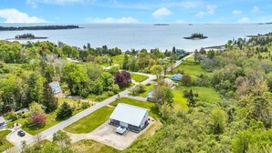 A residential area with a large house, a garage, and a driveway leading to a dock. - Ocean Breeze Haven - Short walk from Crescent Beac (Owls Head)