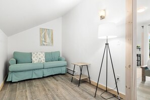 Una sala de estar moderna con un sofá color turquesa, una mesita de madera, una lámpara de pie y un cuadro en la pared.