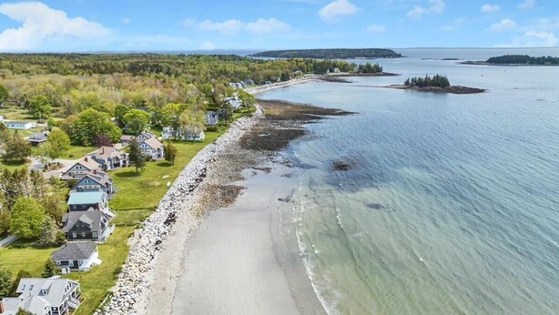 An aerial view of a coastal area with houses along a rocky shoreline, a sandy beach, and a calm sea. - Ocean Breeze Haven - Short walk from Crescent Beac (Owls Head)