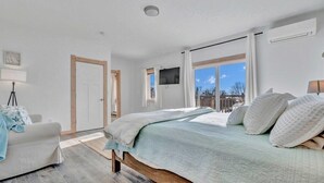 A bedroom with a bed, a TV, a window, and a door. - Ocean Breeze Haven - Short walk from Crescent Beac (Owls Head)