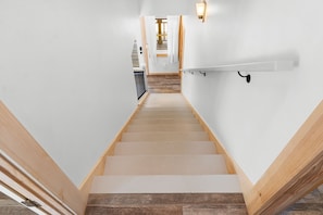 Una escalera con escalones de madera y paredes blancas que conduce a una habitación con piso de madera.