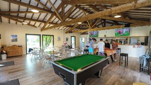 A billiards table in a room with wooden beams, tables, chairs, a bar area, and a television screen. - Cocooning Tipi - Azur (Azur)