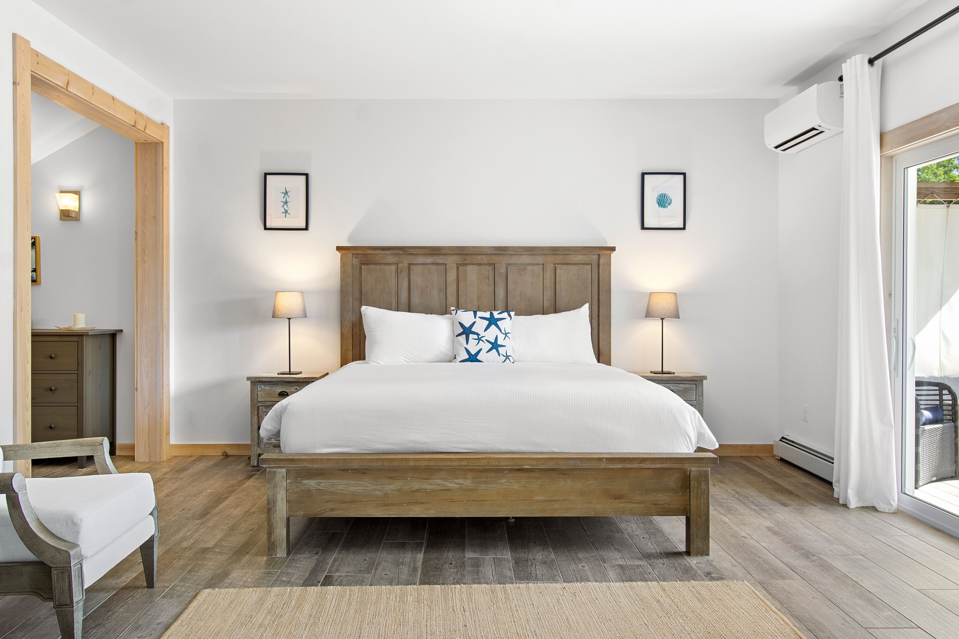 A bedroom with a wooden bed, two bedside lamps, a nightstand, a chair, and a large mirror.