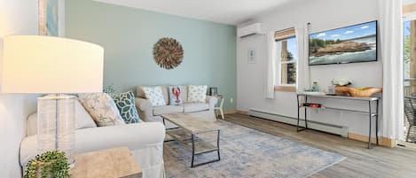 A modern living room with a sofa, coffee table, and a TV mounted on the wall.