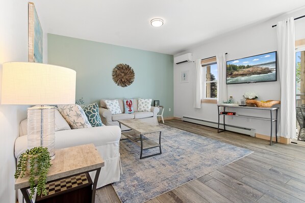A modern living room with a sofa, coffee table, and a TV mounted on the wall.