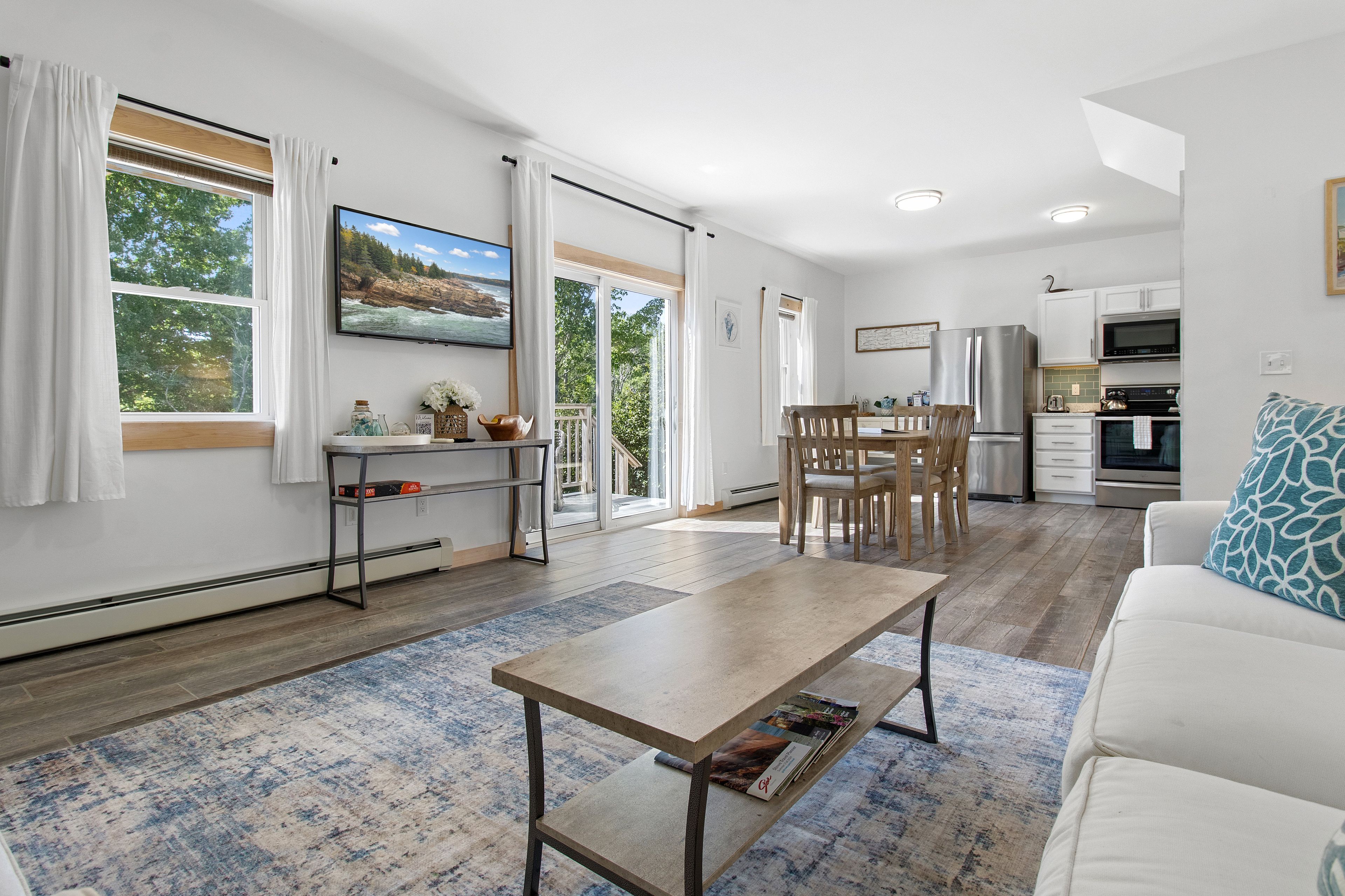 A modern living space with a dining area, kitchen, and a large window with a view of the outdoors.