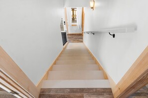 A staircase with wooden steps and white walls, leading to a room with a wooden floor.