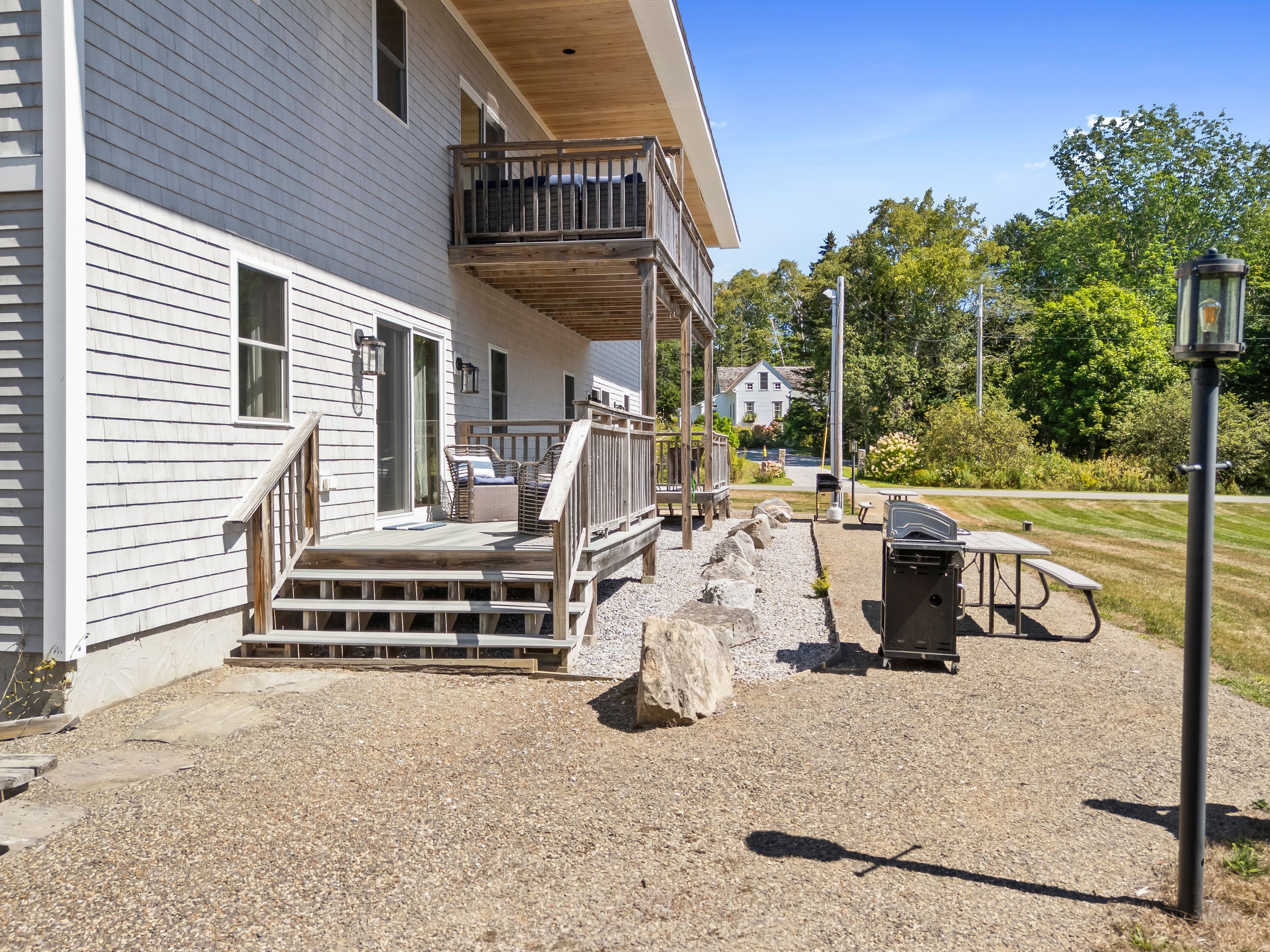 A house with a porch, outdoor seating, and a barbecue grill.