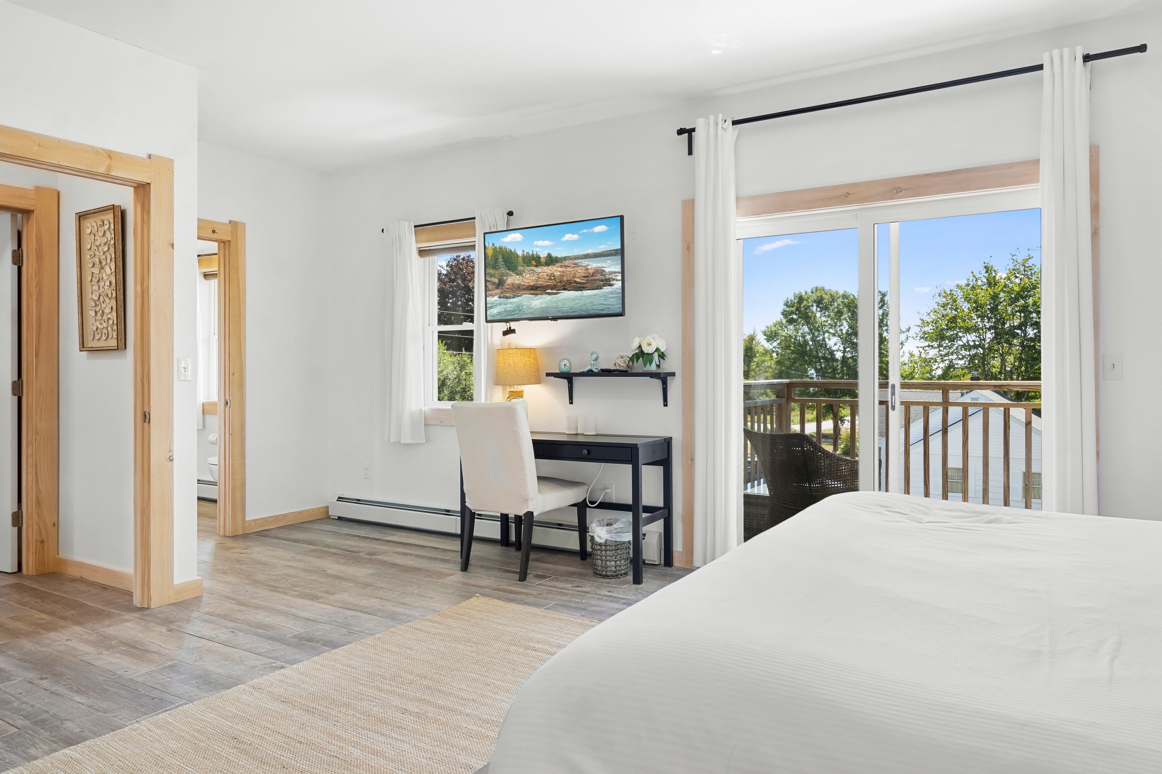 Un dormitorio con cama, escritorio con silla, televisor y ventana con vista al exterior.