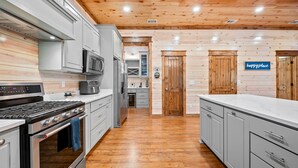 Cocina moderna con electrodomésticos de acero inoxidable, techo de madera y un letrero que dice 'happy place'.