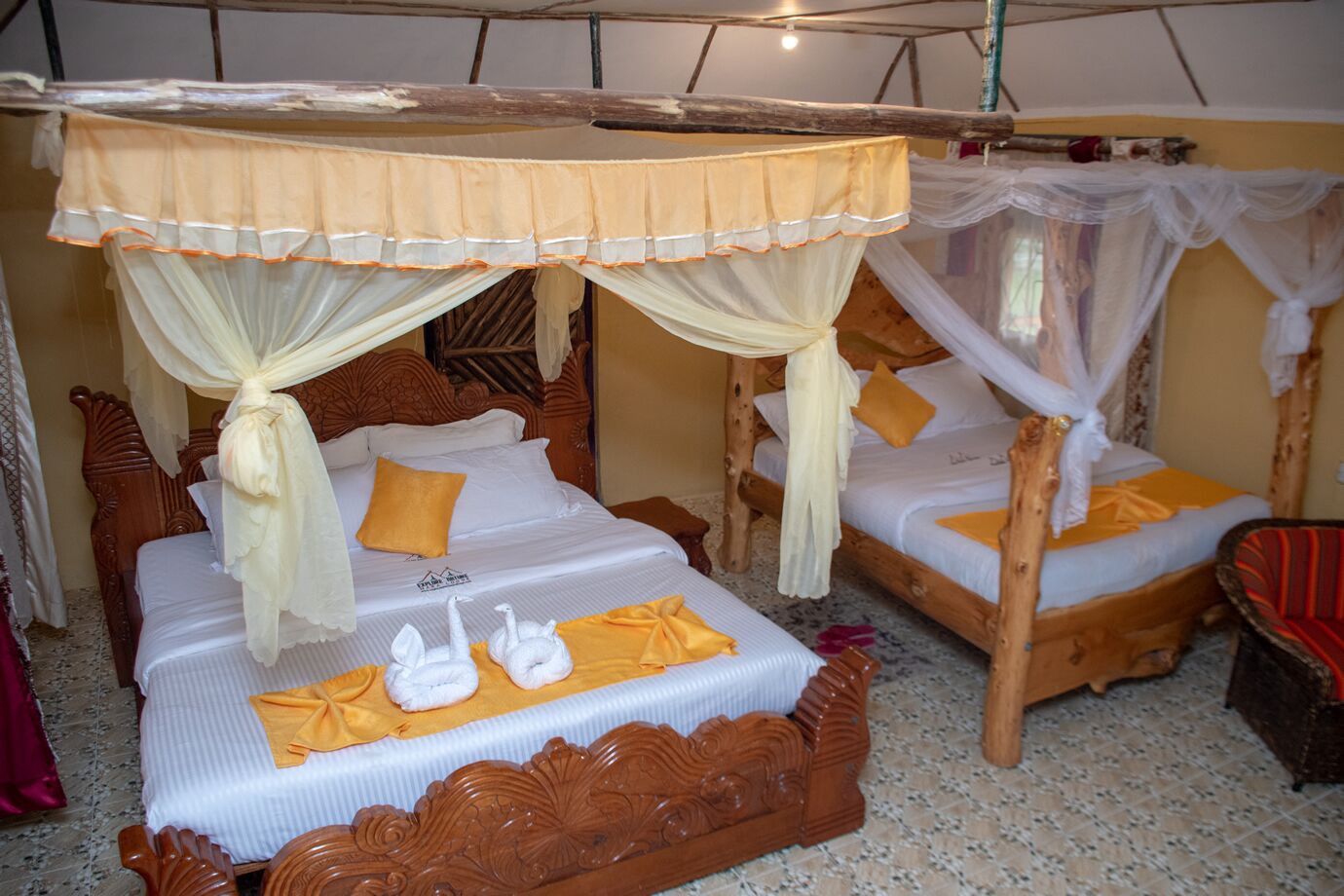 A room with two wooden beds, each with a canopy bedspread and a single white swan-shaped pillow.