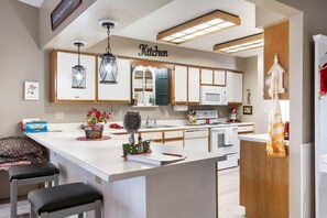 Una cocina moderna con una isla central, iluminación colgante y un letrero que dice 'Kitchen' sobre los armarios.
